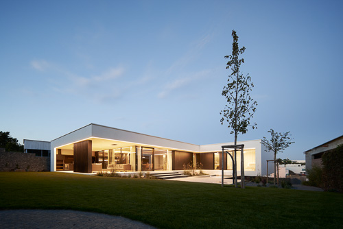 Podvečerní vila v Lysolajích od AV Architekti se zahradou a stromky.