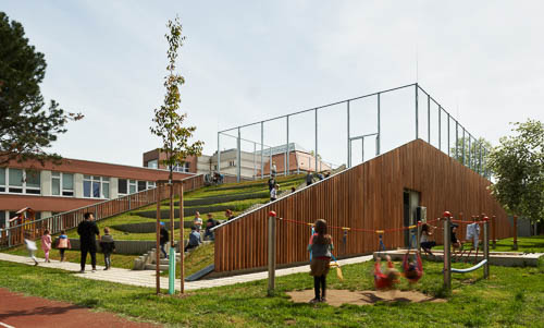 Architektura sportovní haly v Praze s dřevěným opláštěním od Arch Design. Fotografie architektury spojená s životem dětí na školním hřišti.