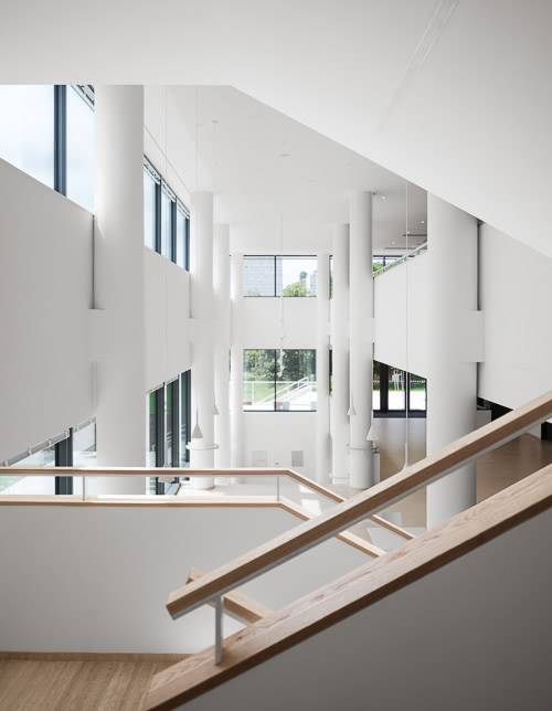 Fotografie průhledu ze schodů na vstupní halu budovy IMPAKT Univerzity Karlovy v Tróji.